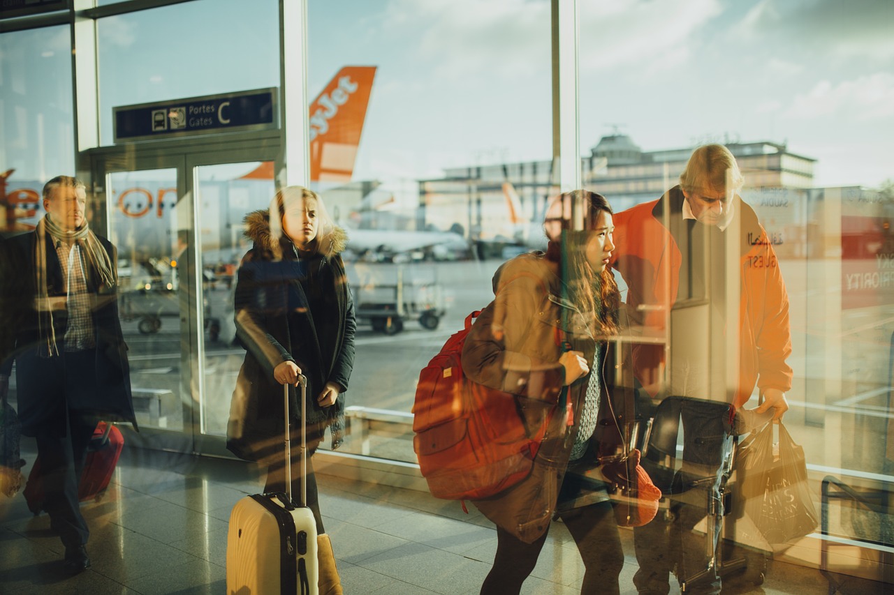 wakacje z biurem podróży czy samodzielnie - ludzie na lotnisku z bagażami